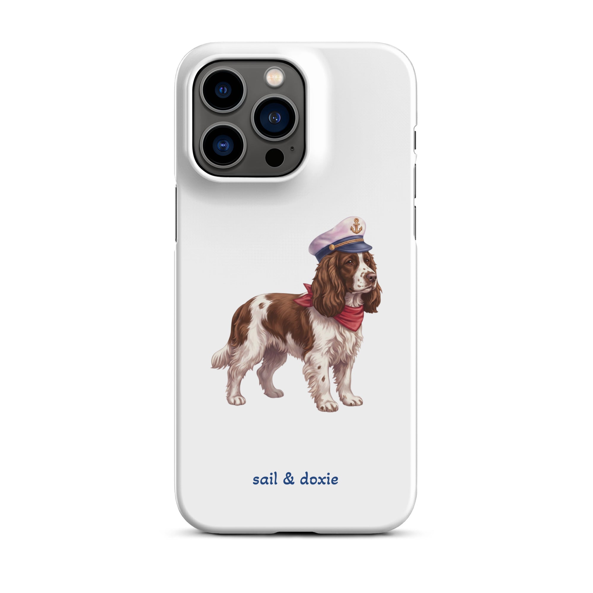 A white phone case featuring an illustration of a brown and white springer spaniel wearing a navy blue captain's hat and red neck scarf, with the text 'sail & doxie' printed in blue below. 