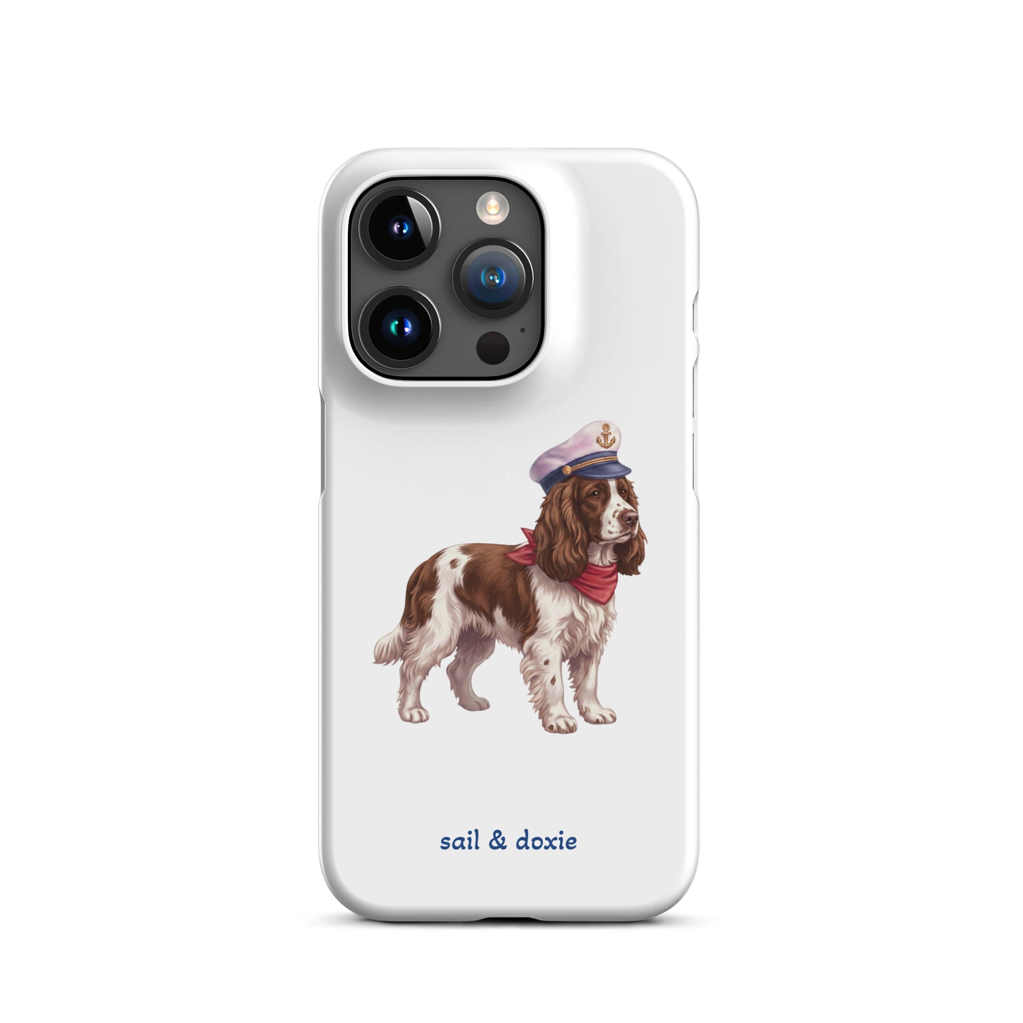 A white phone case featuring an illustration of a brown and white springer spaniel wearing a navy blue captain's hat and red neck scarf, with the text 'sail & doxie' printed in blue below. 