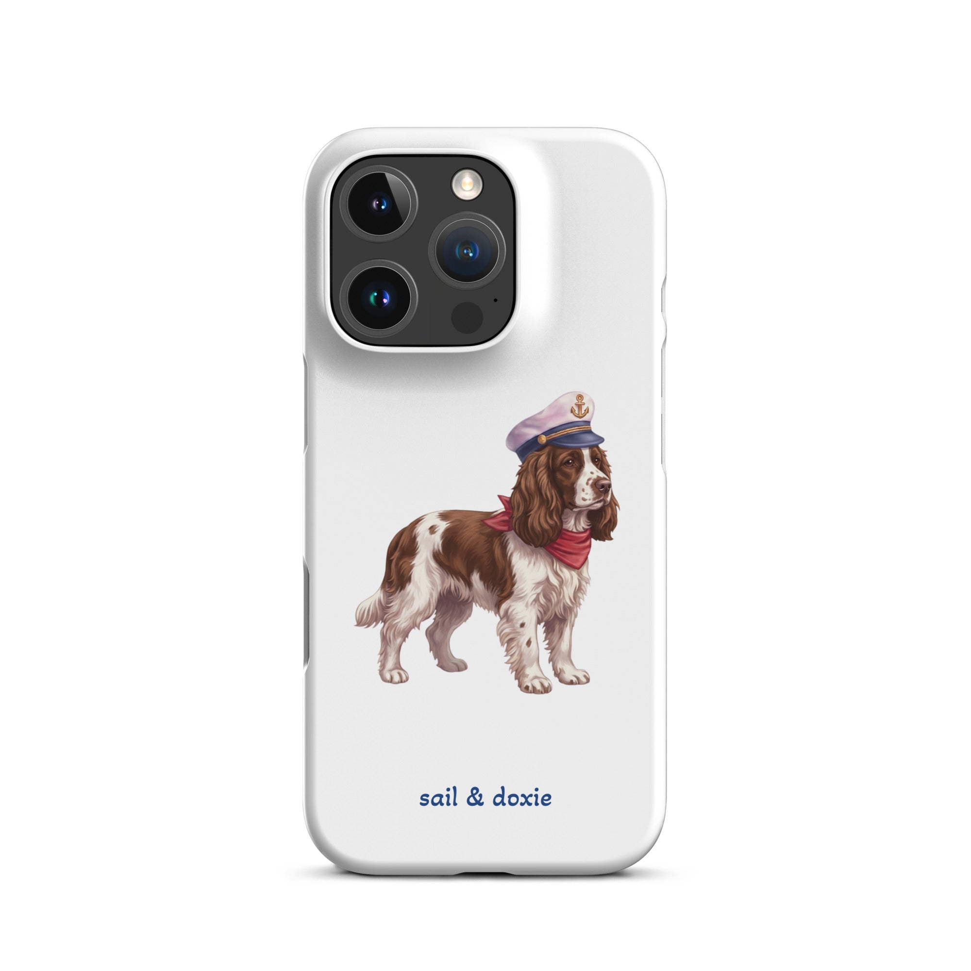 A white phone case featuring an illustration of a brown and white springer spaniel wearing a navy blue captain's hat and red neck scarf, with the text 'sail & doxie' printed in blue below. 