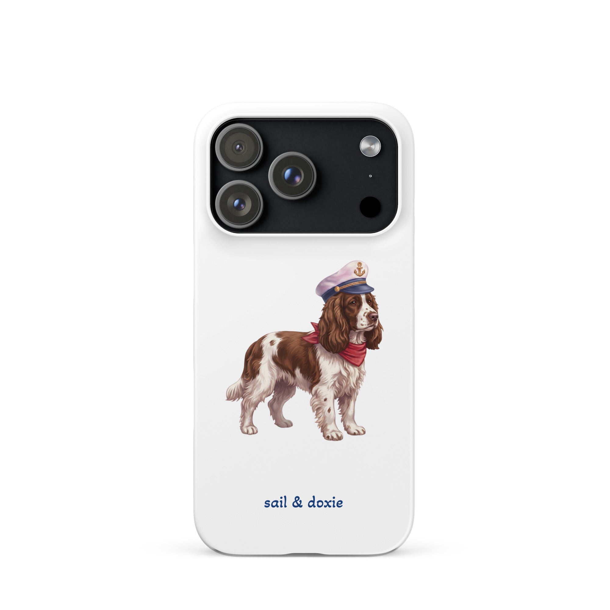 A white phone case featuring an illustration of a brown and white springer spaniel wearing a navy blue captain's hat and red neck scarf, with the text 'sail & doxie' printed in blue below. 